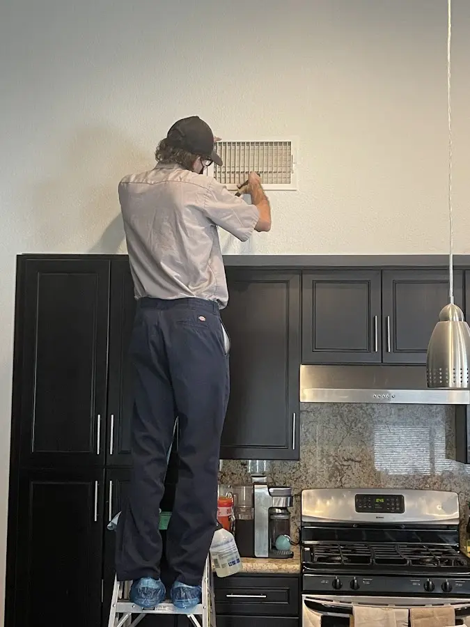 Technician inspecting an air vent during HVAC service in Blakely